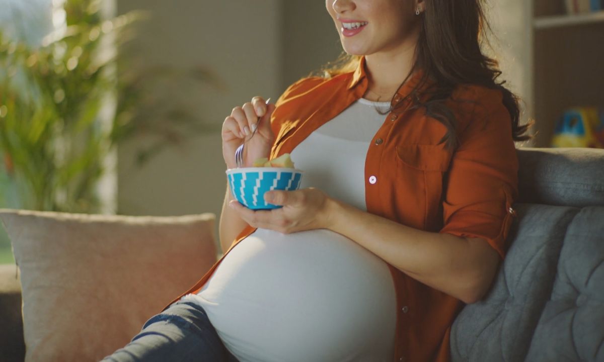 trudnica drži činiju sa jabukama i jede